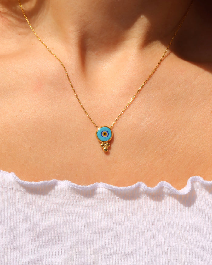 Woman wearing an 18k gold-plated evil eye necklace with a turquoise murano glass evil eye made in Greece, Greek evil eye jewelry