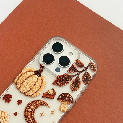 A clear phone case decorated with autumn-themed graphics including a pumpkin, moon, mushrooms, acorns, stars, and leaves.