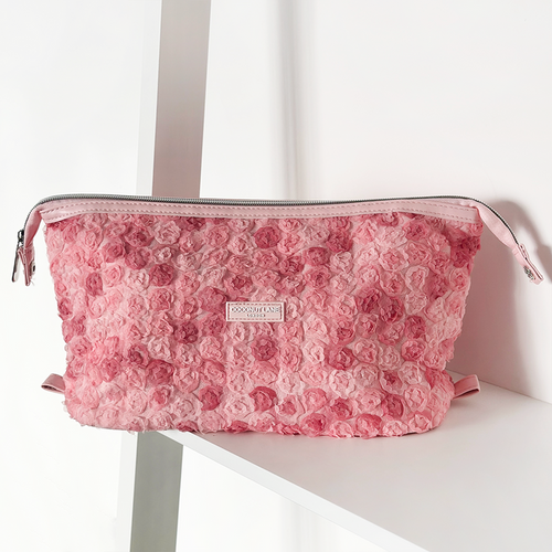 Pink textured Coconut Lane Peony Bloom expandable makeup bag with zipper, displayed on a white shelf.