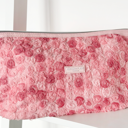 Pink expandable makeup bag with a textured rose pattern from Coconut Lane.