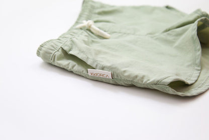 Elastic waistband detail on sage green swim trunks