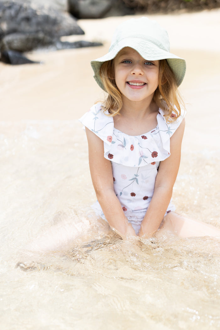 Girl playing in Lalliana coconut ruffle swimsuit by KidORCA