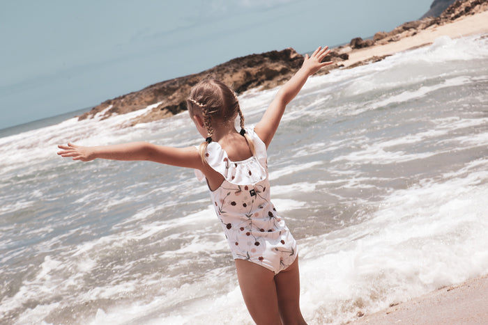 Girl playing in Lalliana coconut ruffle swimsuit by KidORCA