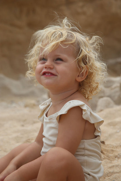 Girl playing in almond waffle weave swimsuit variant by KidORCA