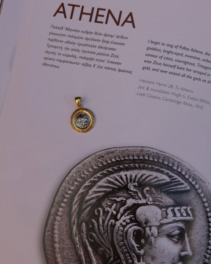 Silver replica ancient Greek coin featuring Athena, the Greek goddess of wisdom wearing a helmet, surrounded by an 18k gold-plated Greek key meander frame. Greek mythology jewelry