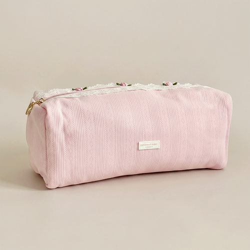 Pink pointelle fabric hair tool bag with Coconut Lane logo badge. White lace trim detailing.