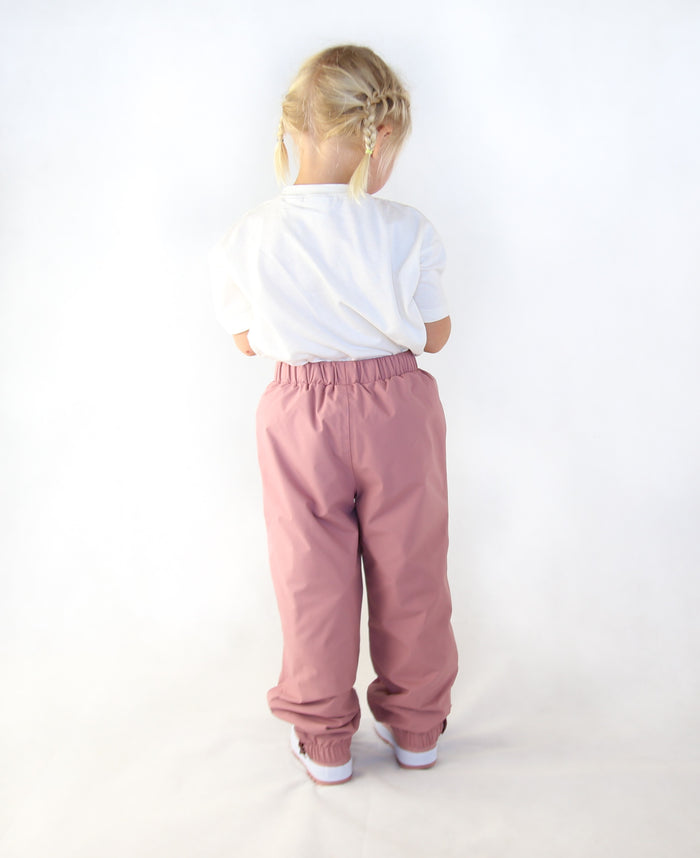 Child wearing ash-rose waterproof rain pants by KidORCA