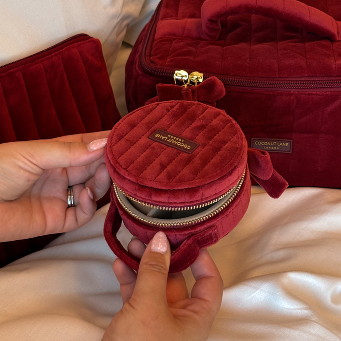 Burgundy velvet jewellery box with a quilted design, top handle, bow detail, and gold-tone hardware.