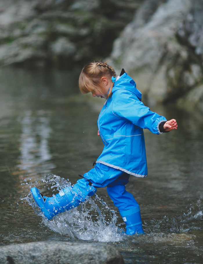 Child splashing in blue rain boots with above-knee waders by KidORCA