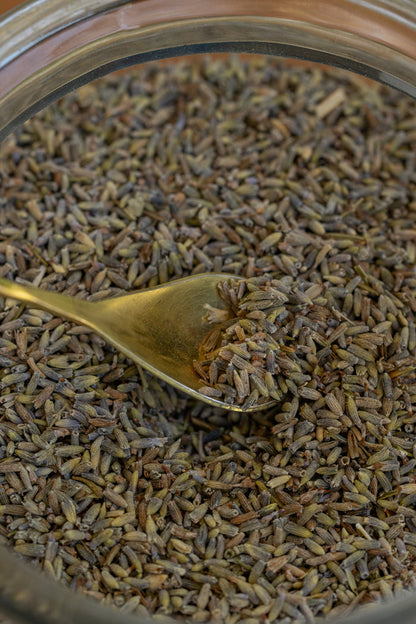 Close-up of a spoonful of dried lavender flowers over a jar filled with lavender.