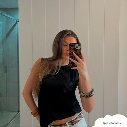 Woman with long hair wearing a black top holds a Coconut Lane phone case with a brown leopard tortoiseshell pattern.
