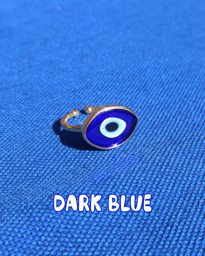 Dark blue Murano glass evil eye ring with a gold band against a blue background, Greek evil eye jewelry