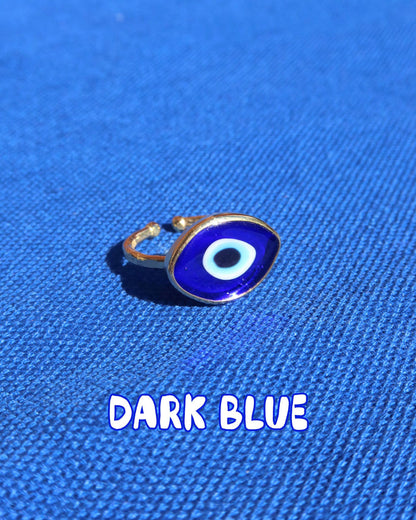 Dark blue Murano glass evil eye ring with a gold band against a blue background, Greek evil eye jewelry