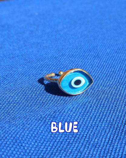 Light blue Murano glass evil eye ring with a gold band against a blue background, Greek evil eye jewelry