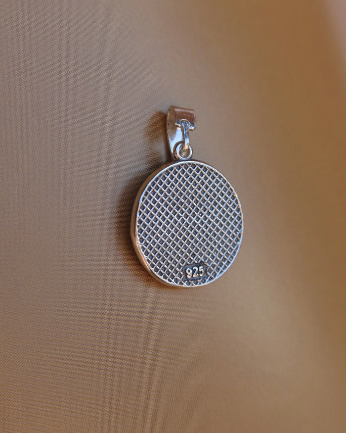 Back side of a silver oxidized pendant with a grid and 925 stamp