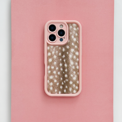 A phone case with pink edging and brown fawn-print center featuring white spots, shown on a phone against a solid pink background.