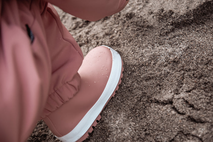 Child wearing ash rose above-knee rain waders – side view