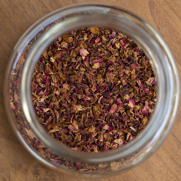 Glass jar filled with dried herbs on a wooden surface