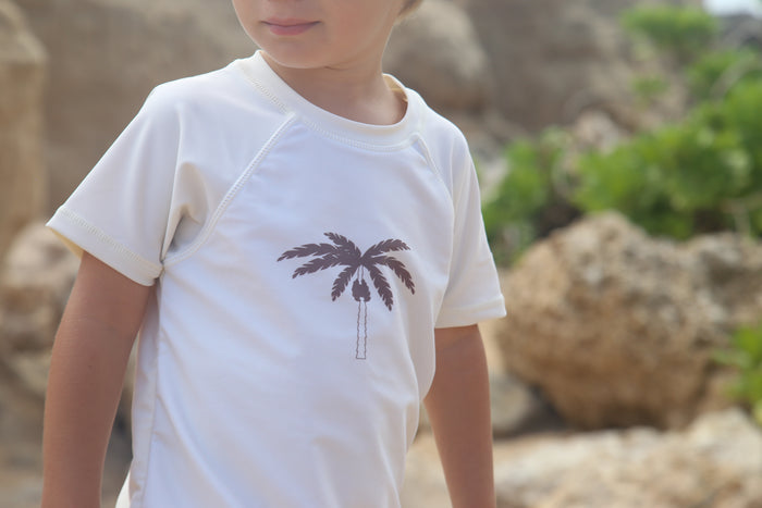 Child playing in palm tree rashguard by KidORCA