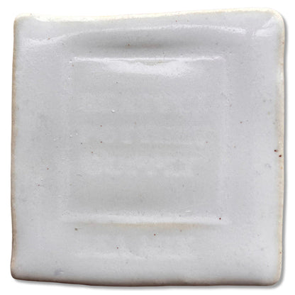 SP32 White Satin glaze on a square test tile, opaque glossy white with faint red speckles