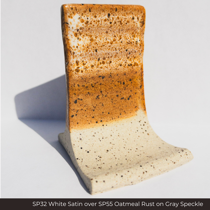 SP32 White Satin glaze over SP55 Oatmeal Rust glaze on a Gray Speckle clay test tile, white mottling on rust orange