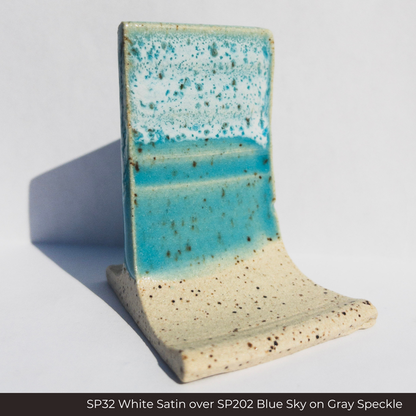 SP32 White Satin glaze over SP202 Blue Sky glaze on a Gray Speckle clay test tile, white mottling on turquoise