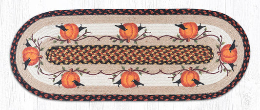 Decorative table runner with pumpkins and crows on a tan background made from braided jute.